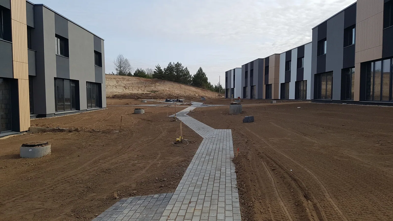 Teritorija tarp gyvenamųjų pastatų su paruoštu gruntu ir taku